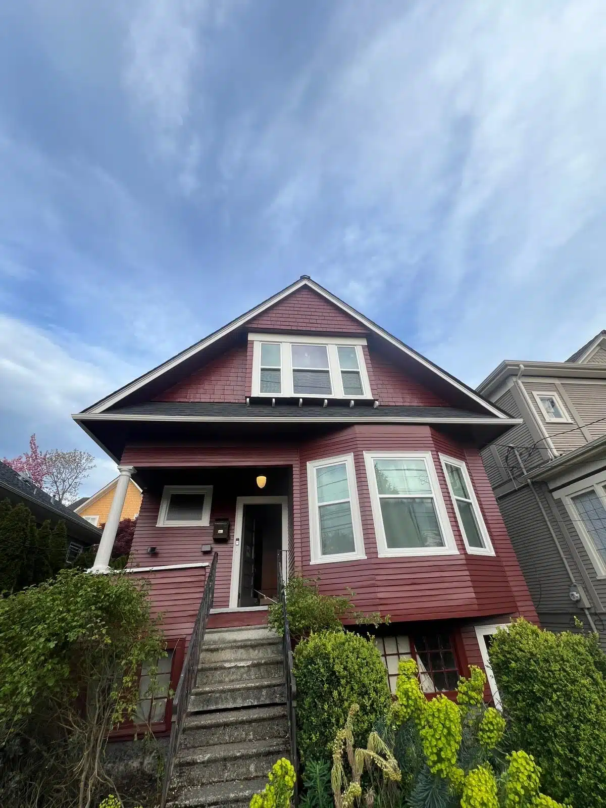 Red House Exterior Painting Service A beautiful red residential house with white trim and a front porch, showcasing professional exterior painting.