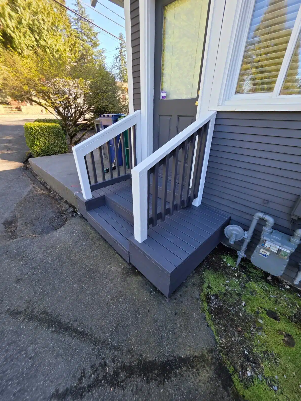 Exterior Steps and Railing Painting Service Newly painted dark gray exterior steps with white and dark gray railings leading to a house entrance.