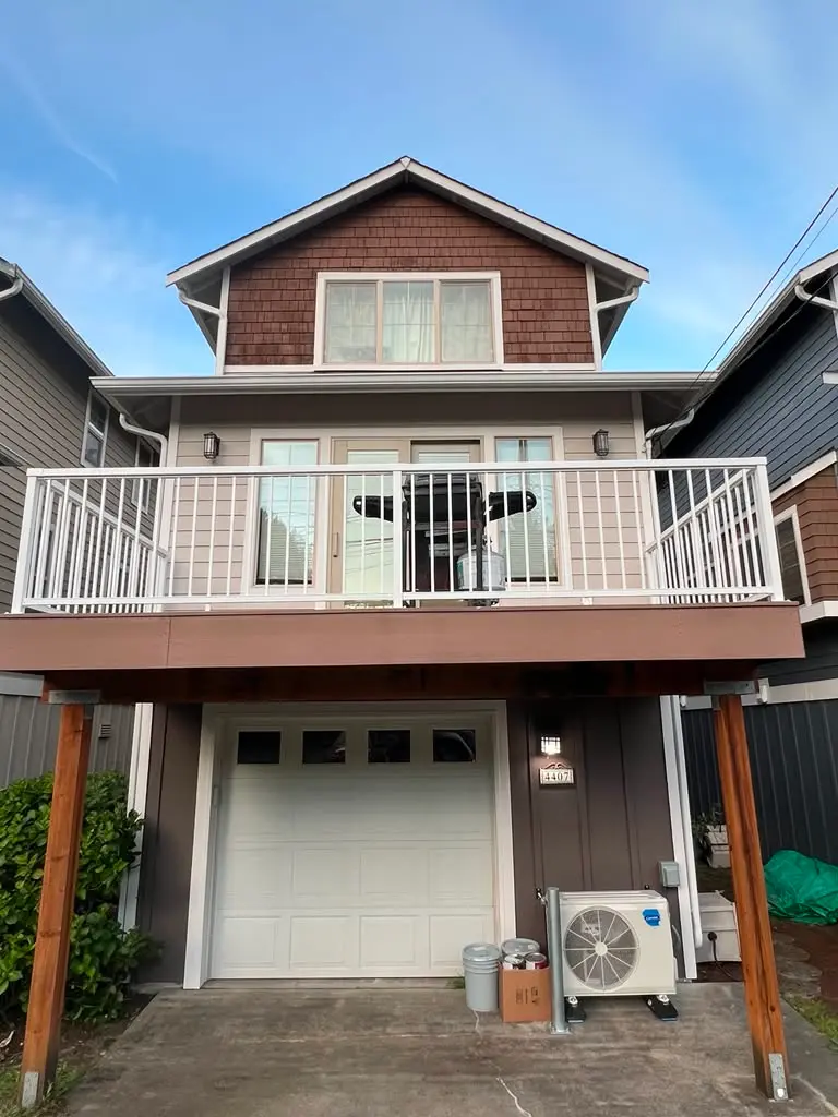Residential Exterior Painting for Homes with Decks and Garages Back view of a multi story residential house with gray siding, a white garage door, and an expansive deck.