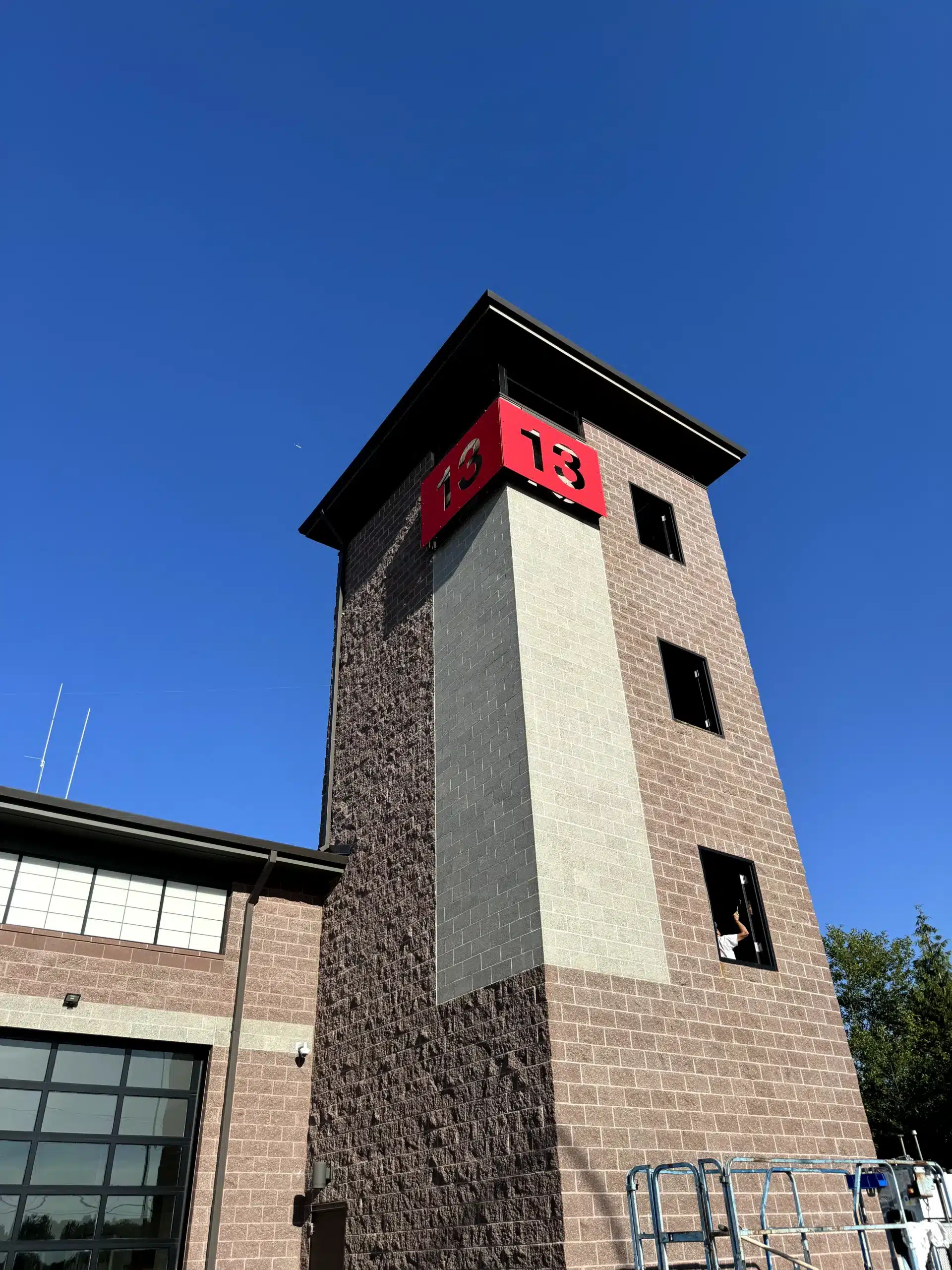 Commercial Building Exterior Painting Services for Fire Stations Professional painters working on the exterior of a commercial fire station building with brick and concrete.